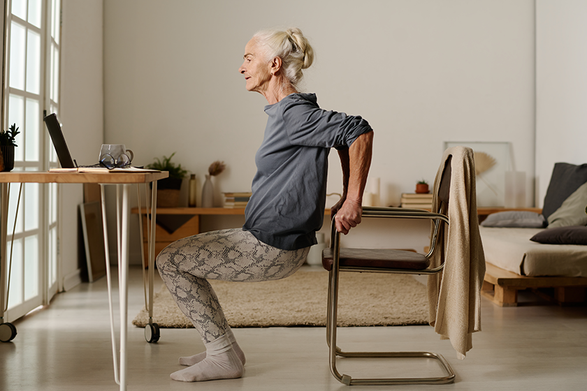 Side view of aged active woman in casualwear doing squats